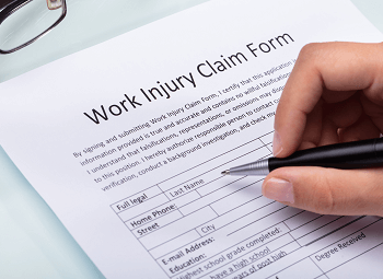 Hand holding a pen ready to fill out a work injury claim form